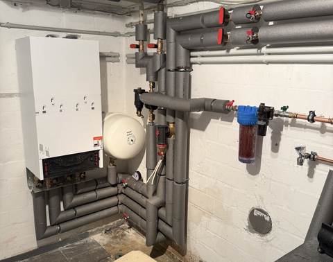Verteiler mit mehreren Absperrventilen und Wärmepumpen-Innenmodul im Heizungskeller